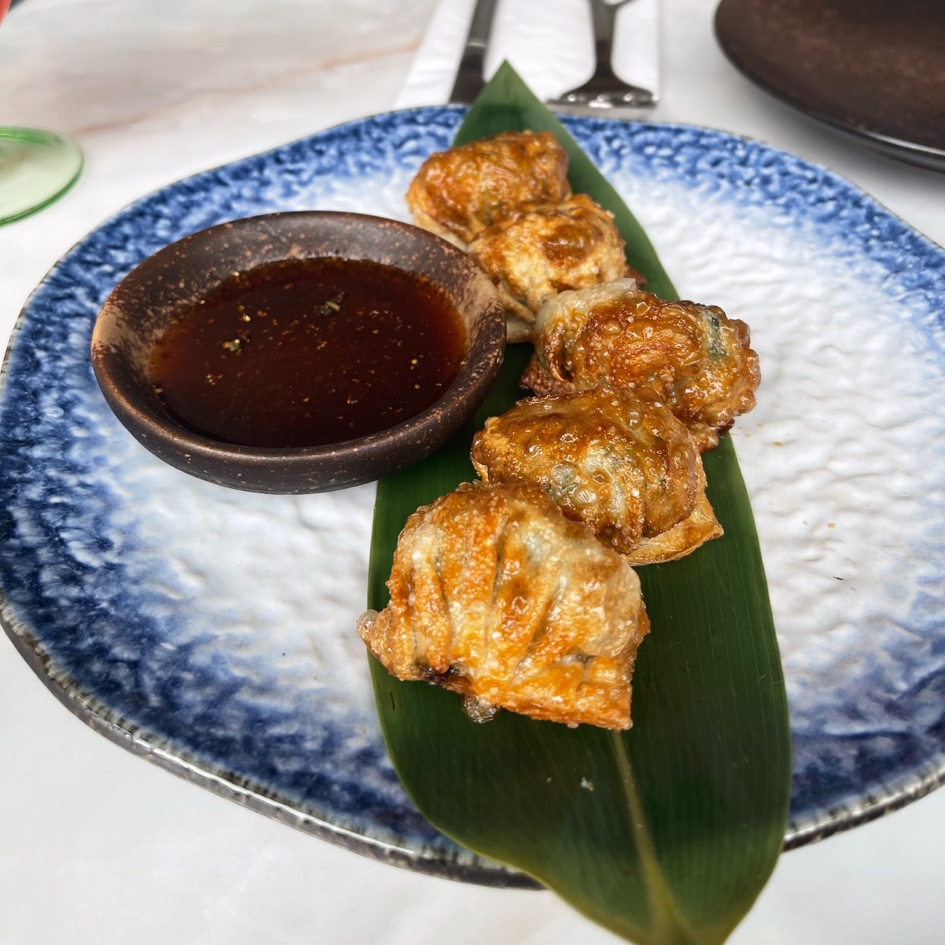 Ebi Gyoza (prawn dumplings) on a banana leaf and sweet dipping sauce. 