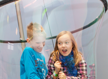 Two children laughing inside a giant bubble
