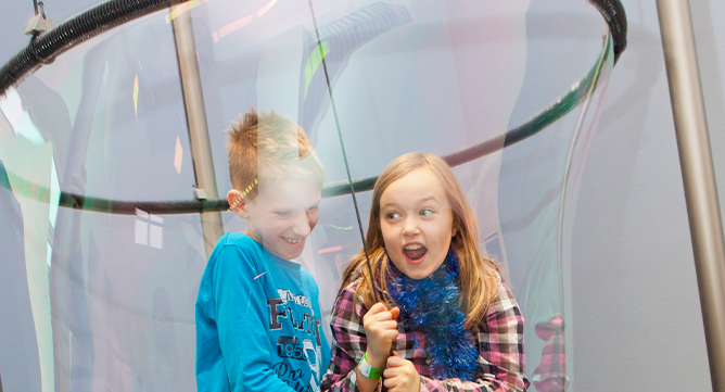 Two children laughing inside a giant bubble