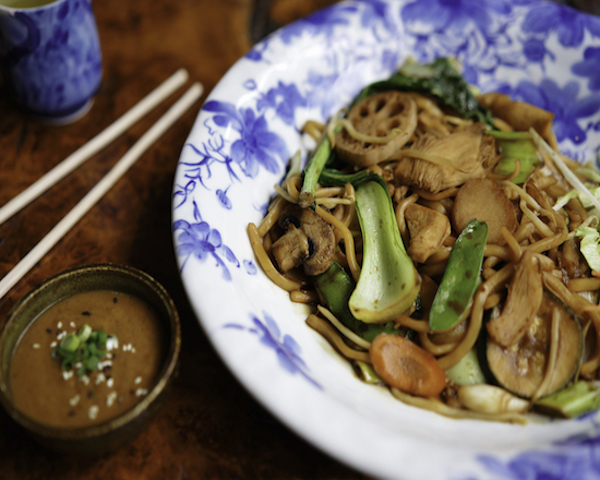 Shallow stir fried noodles with chopsticks in the background.