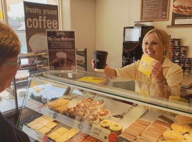 Bakery store assistant is giving a coffee and a leaflet to a customer in a Cooplands store