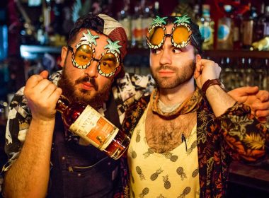 two men with party glasses on and with a bottle of win in their hands