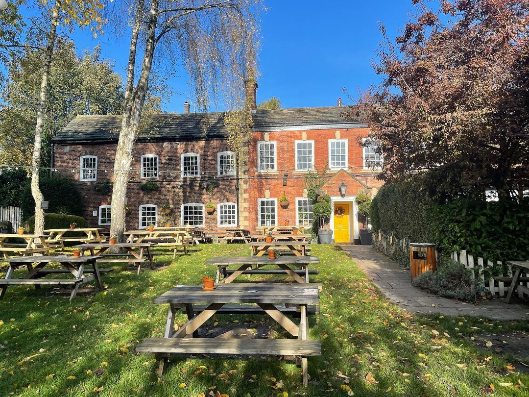 outside of pub with wooden chairs and grass.