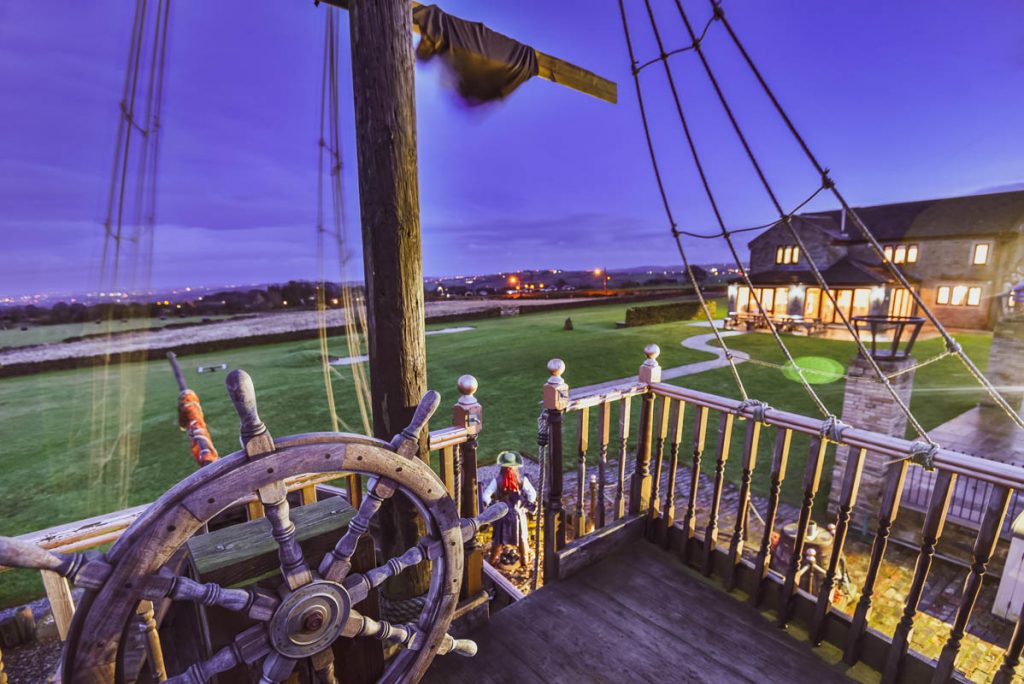 a pirate boat with a wheel in the back garden.