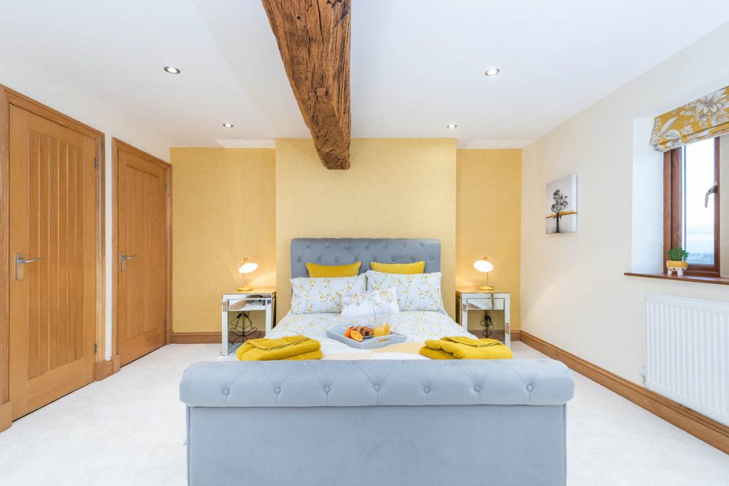 clean airy bedroom pained yellow with a be in the middle.