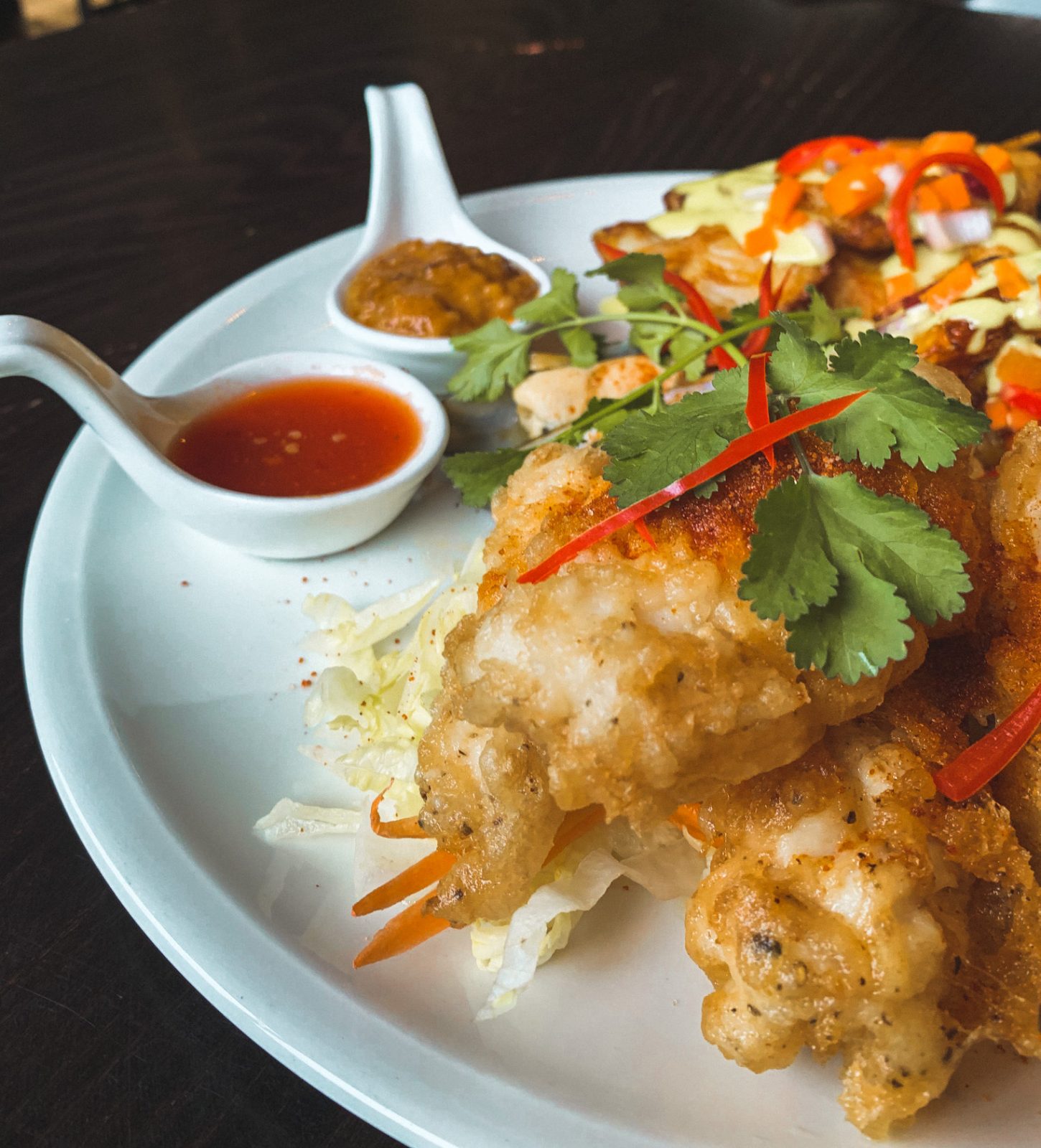 fish on a plate with satay and sweet chilli saice.