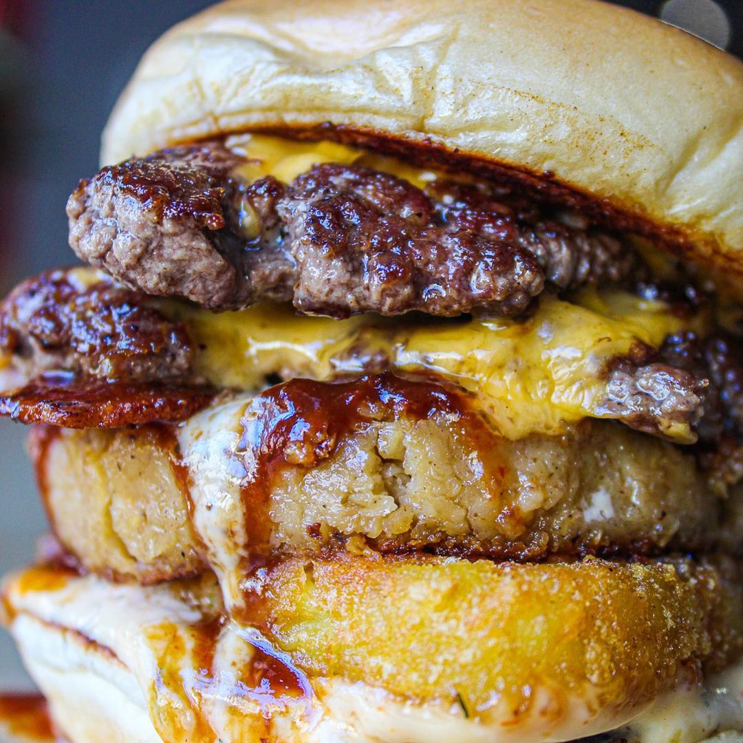burger piled high with hash brown and sauce.