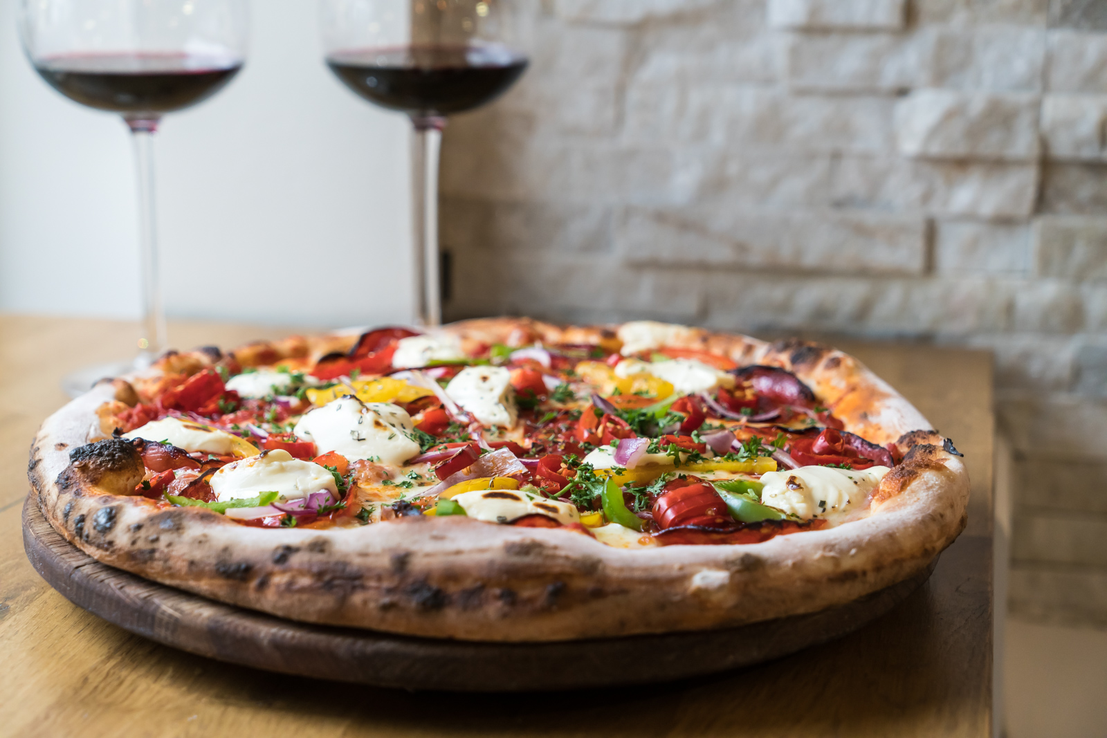 A pizza alongside two glasses of wine at Trattoria Ill Forno.