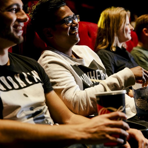 people holding popcorn in the cinema.