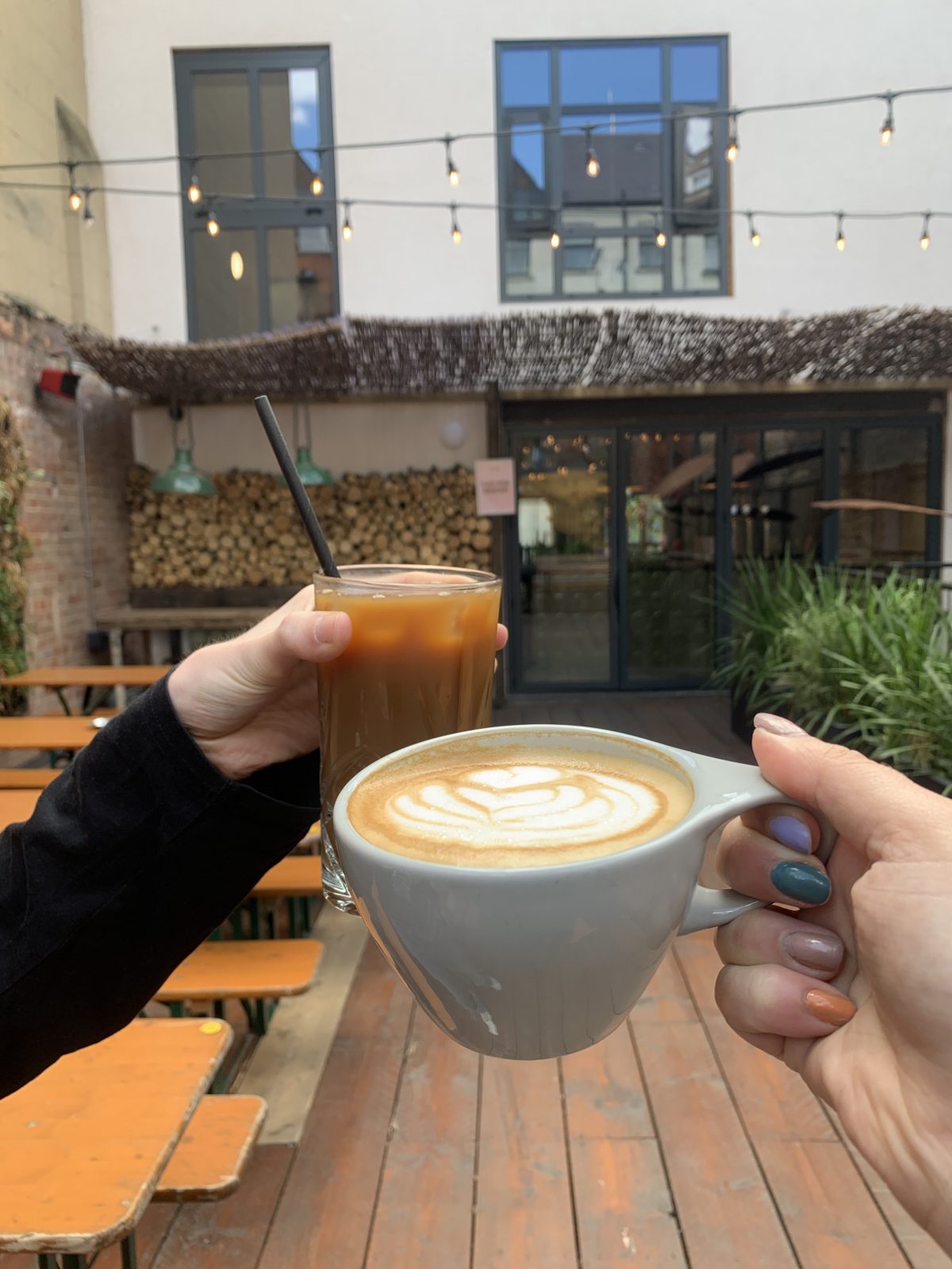 An iced coffee and hot coffee in the sunshine.