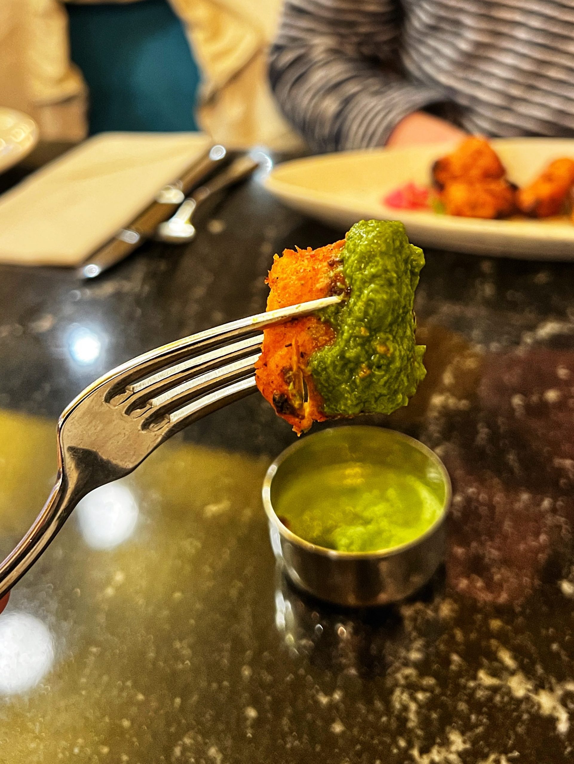 fork holding up square with green sauce.