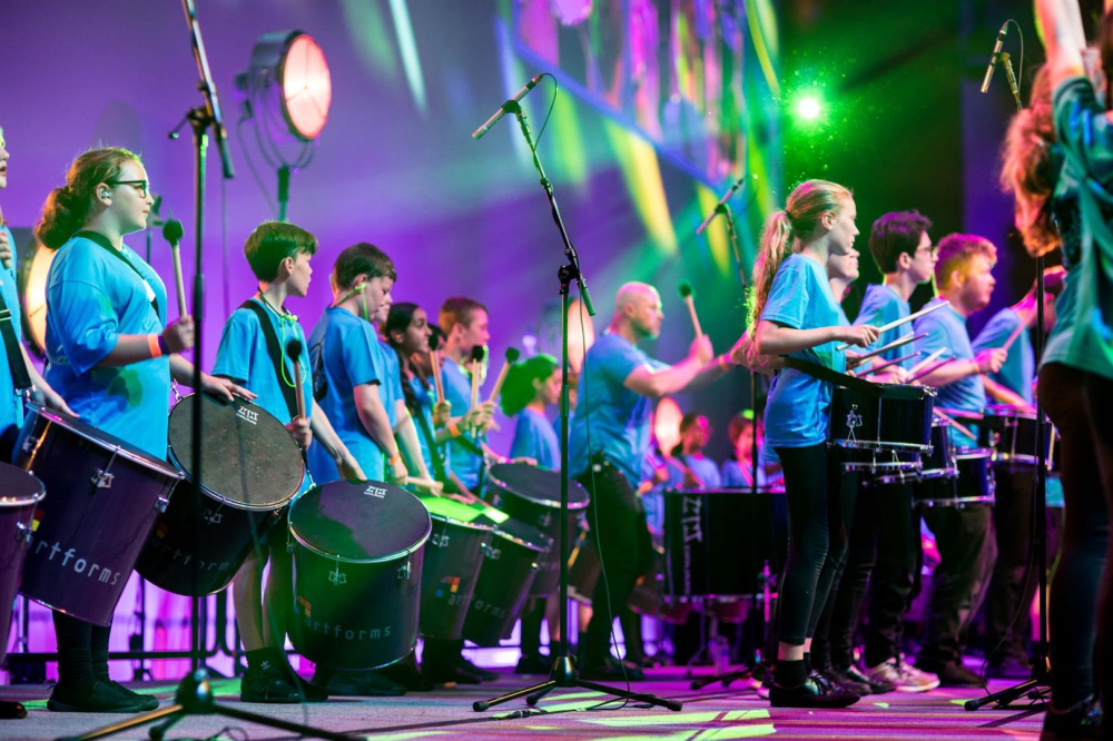 group of children on stage playing drums.