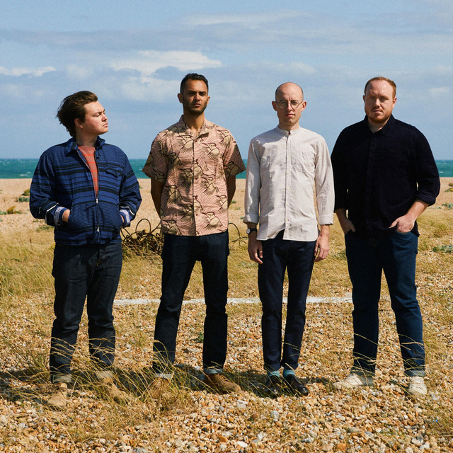 four people stood up in a field from Bombay Bicycle Club.