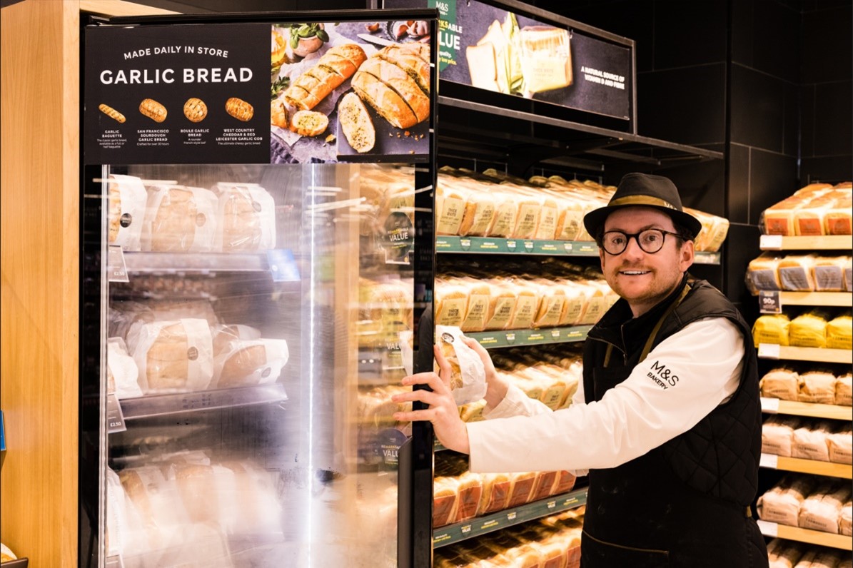 A man opening the garlic bread fridge at M&S.
