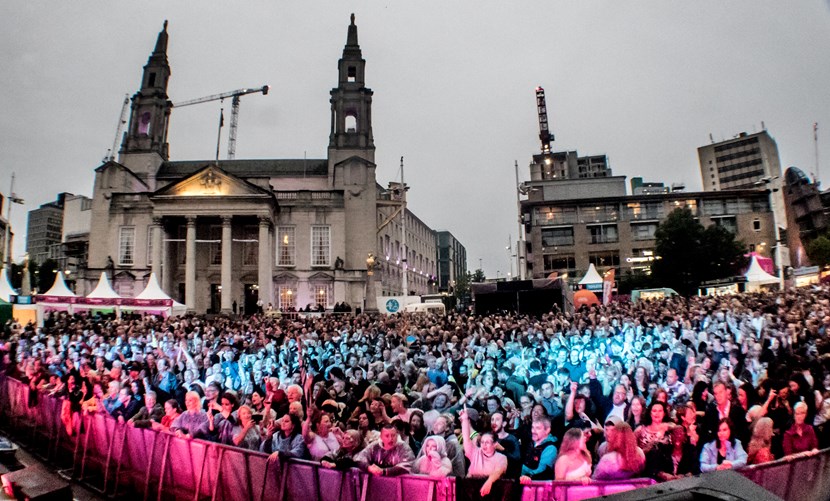 People looking onto the stage at Millennium Square with blue and pink lights reflecting off it.