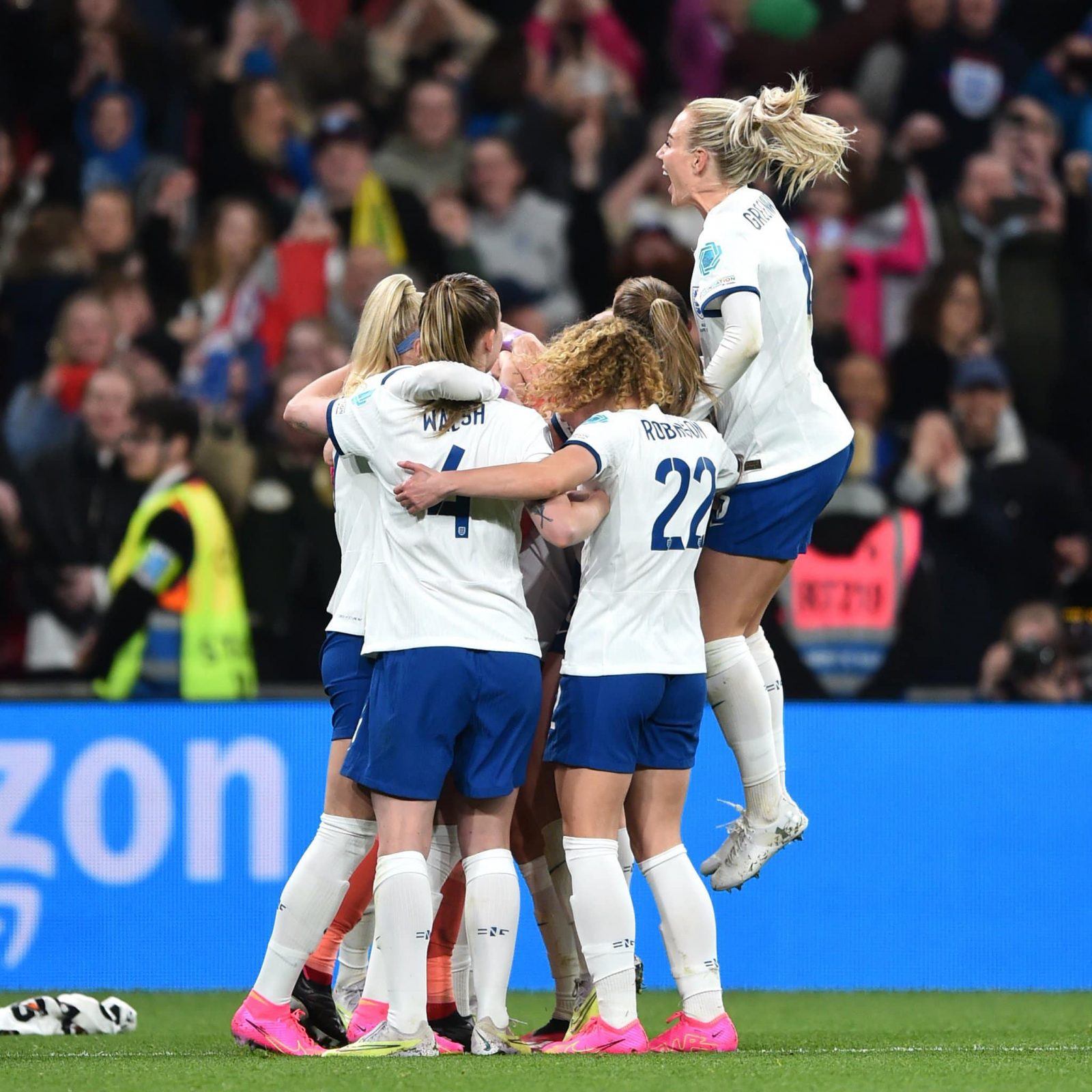The England women's football team hugging on the pitch. 