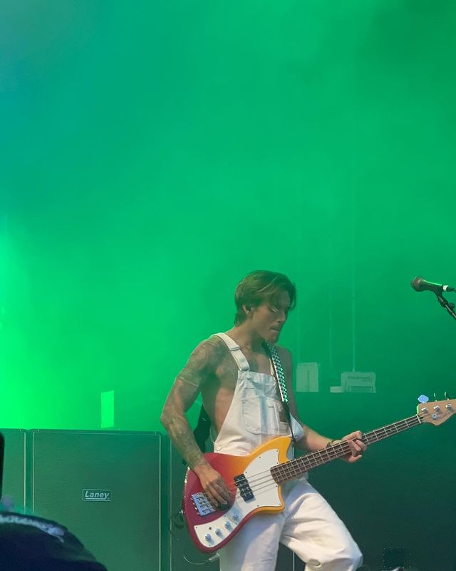 Dougie from band McFly in white dungarees looking perfect with floppy hair strumming a guitar with the aura of a Greek god.