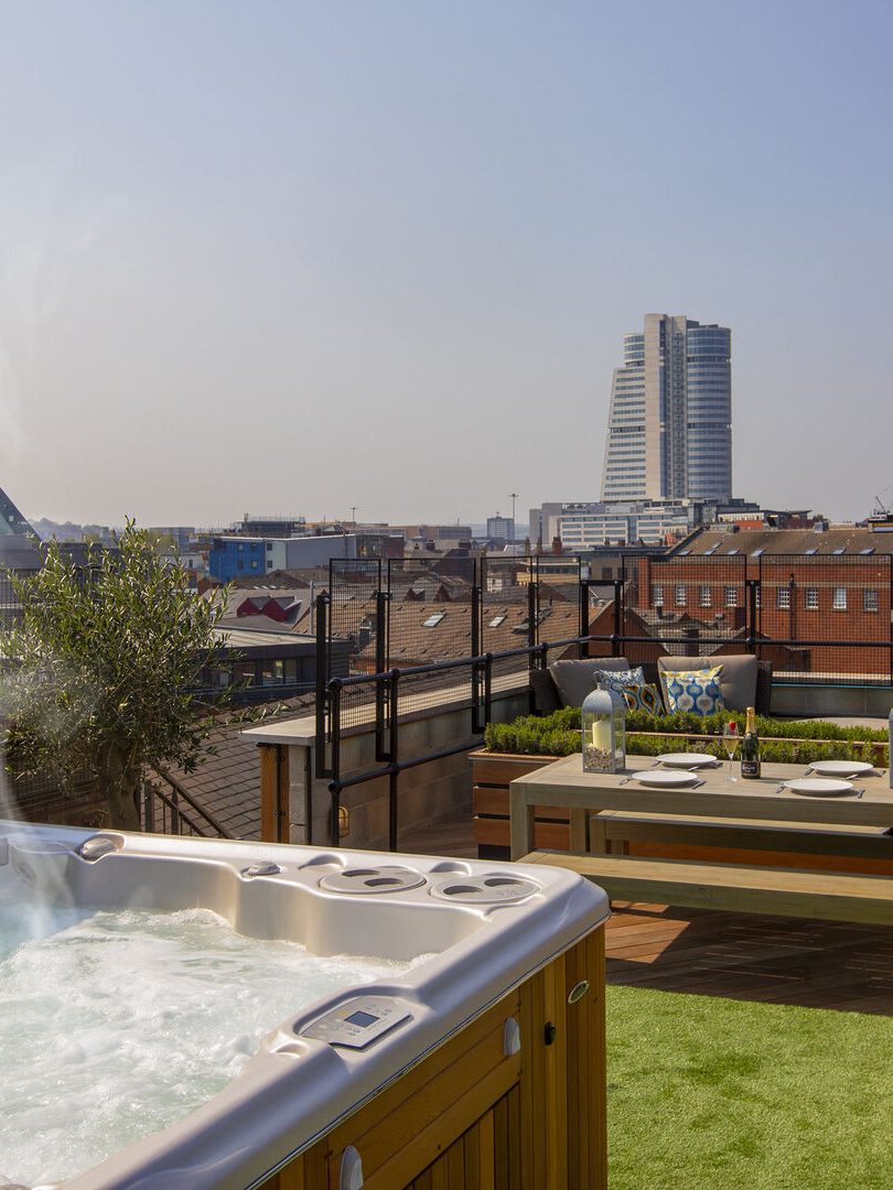 A rooftop overlooking Leeds city centre with a hot tub in the foreground. 