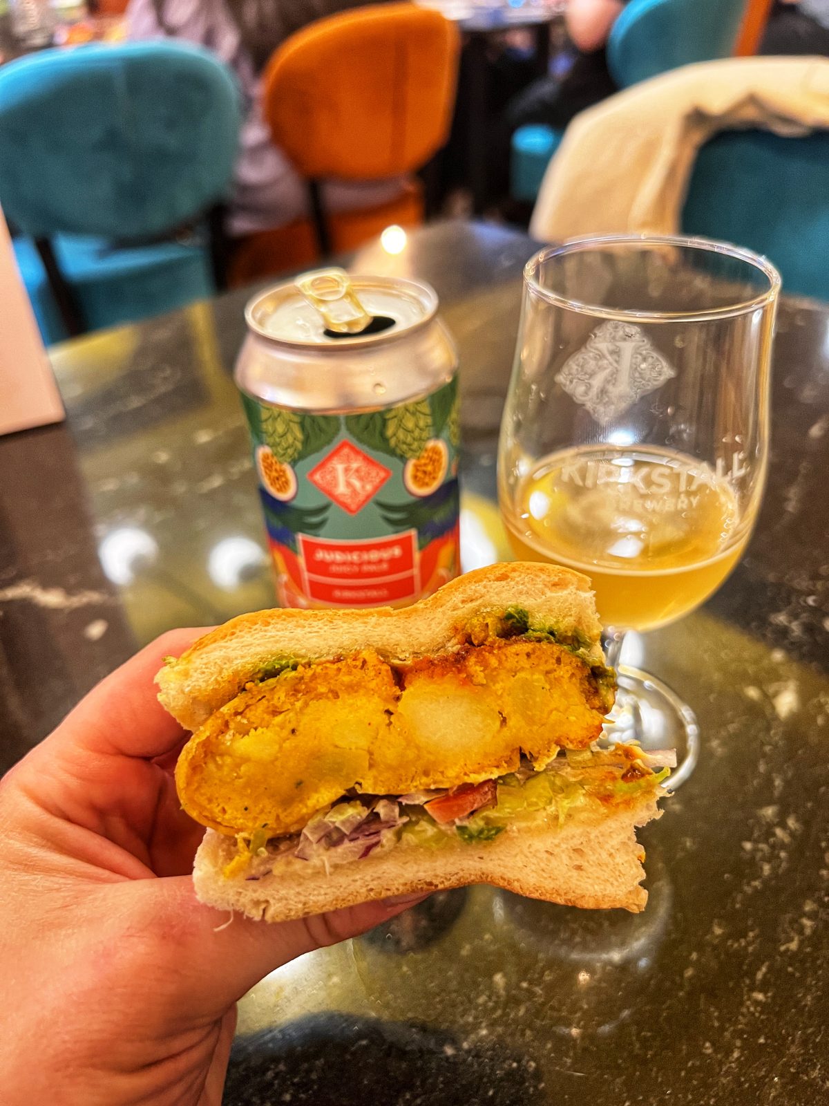 Half a sandwich cut open with beer in background.