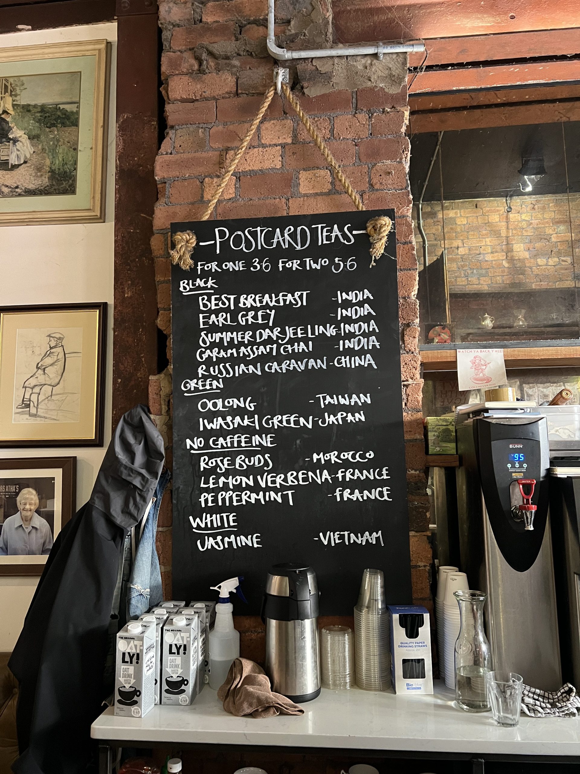 a chalkboard sign with different tea options including rose buds, jasmine and best breakfast.