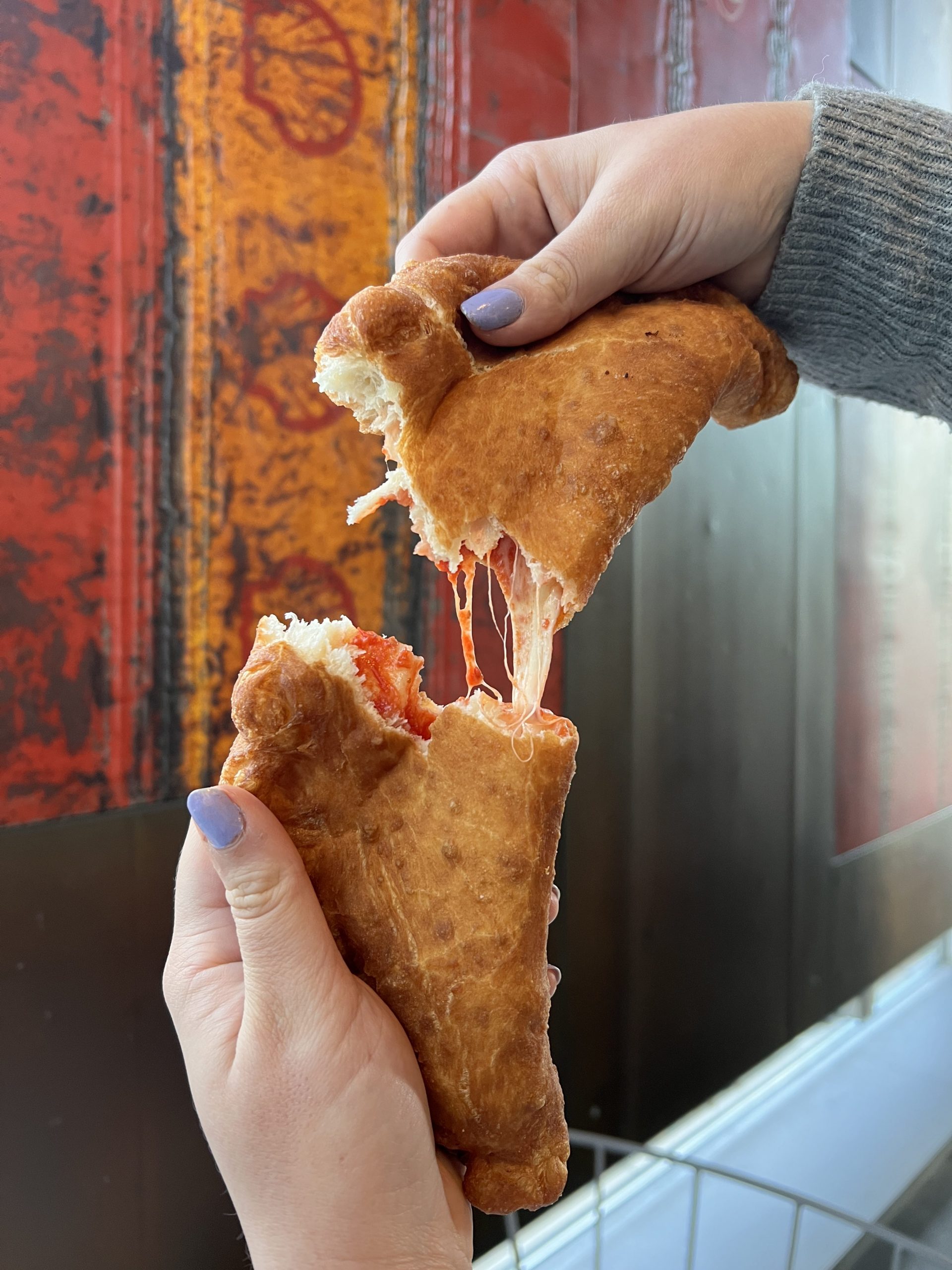 A deep fried calzone being pulled apart. 