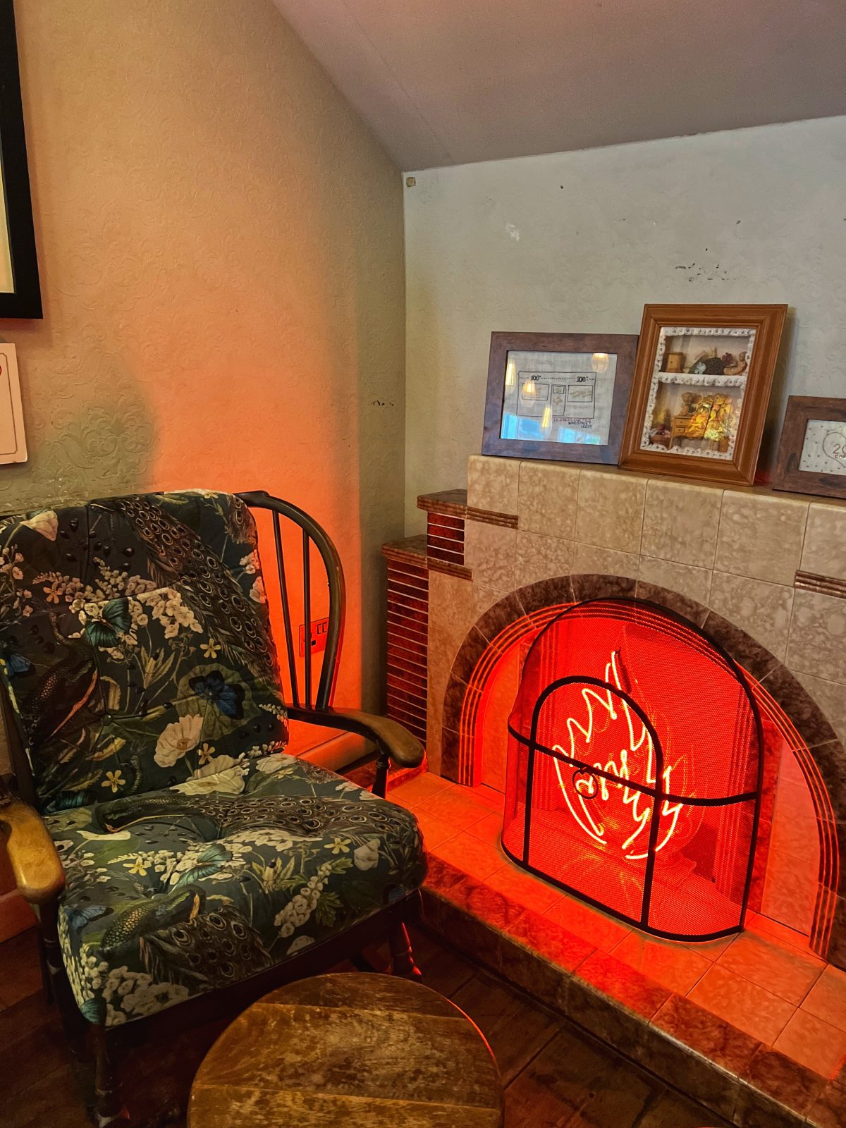 fireplace with a neon sign and pattern sofa on it.