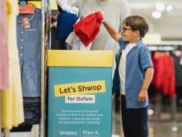A young boy donating clothes to Oxfam in M&S.