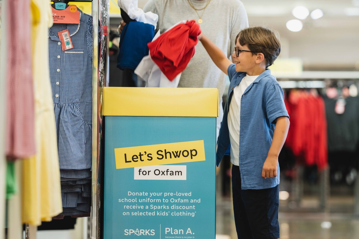 A young boy donating clothes to Oxfam in M&S.
