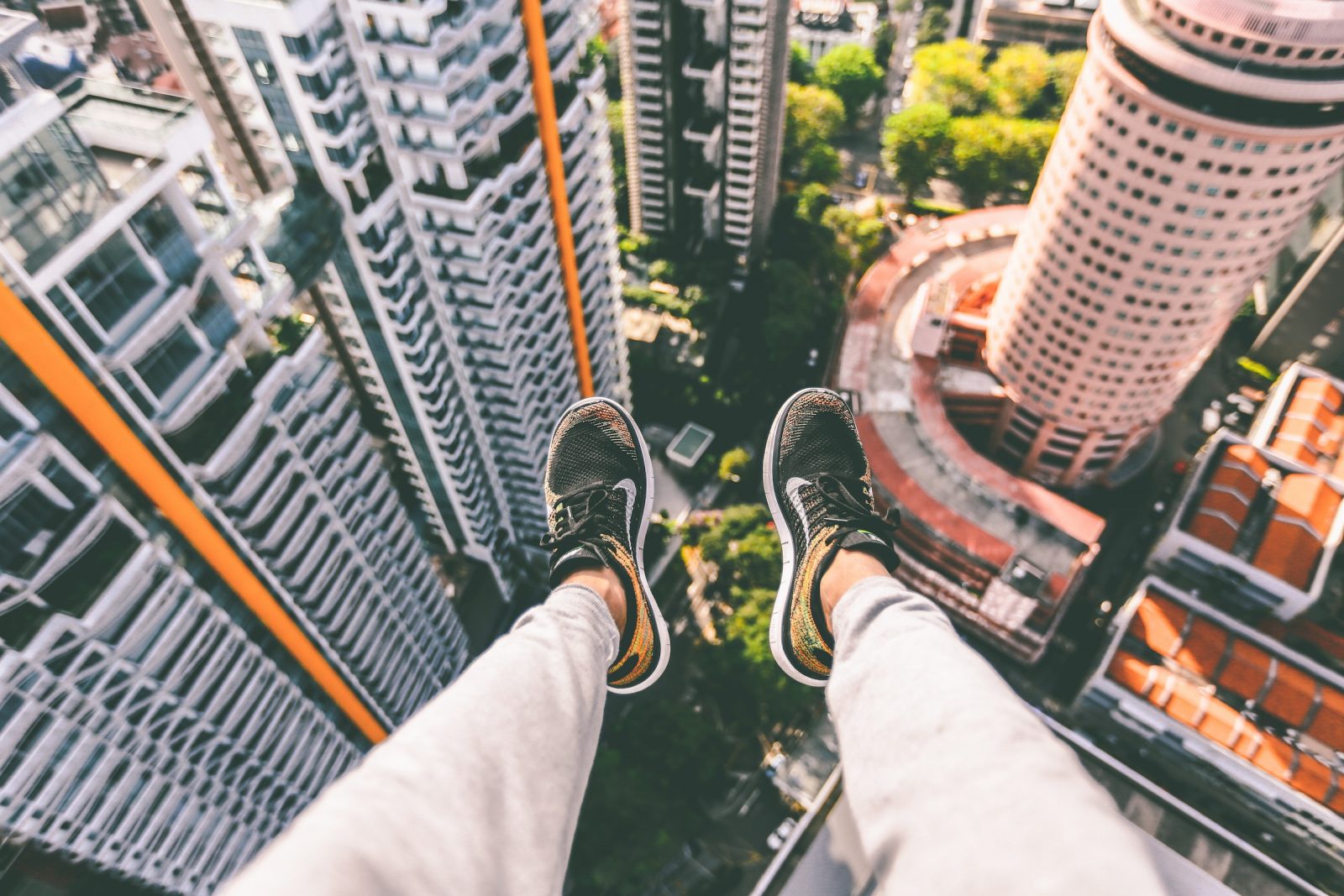 Someone sat on top of a building, looking down at their feet. 