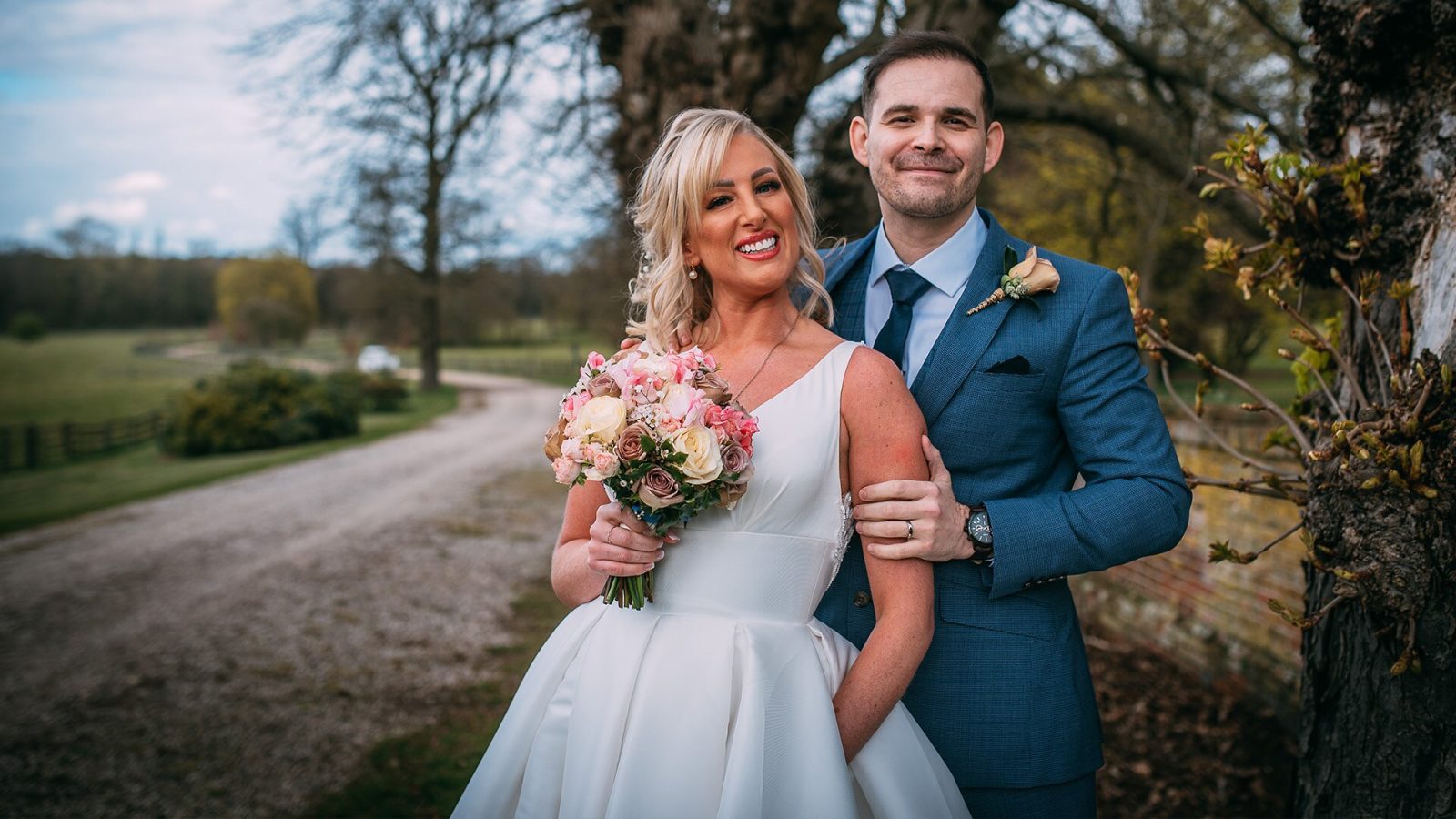 A woman in a wedding dress and a man in a suit smiling to the camera.