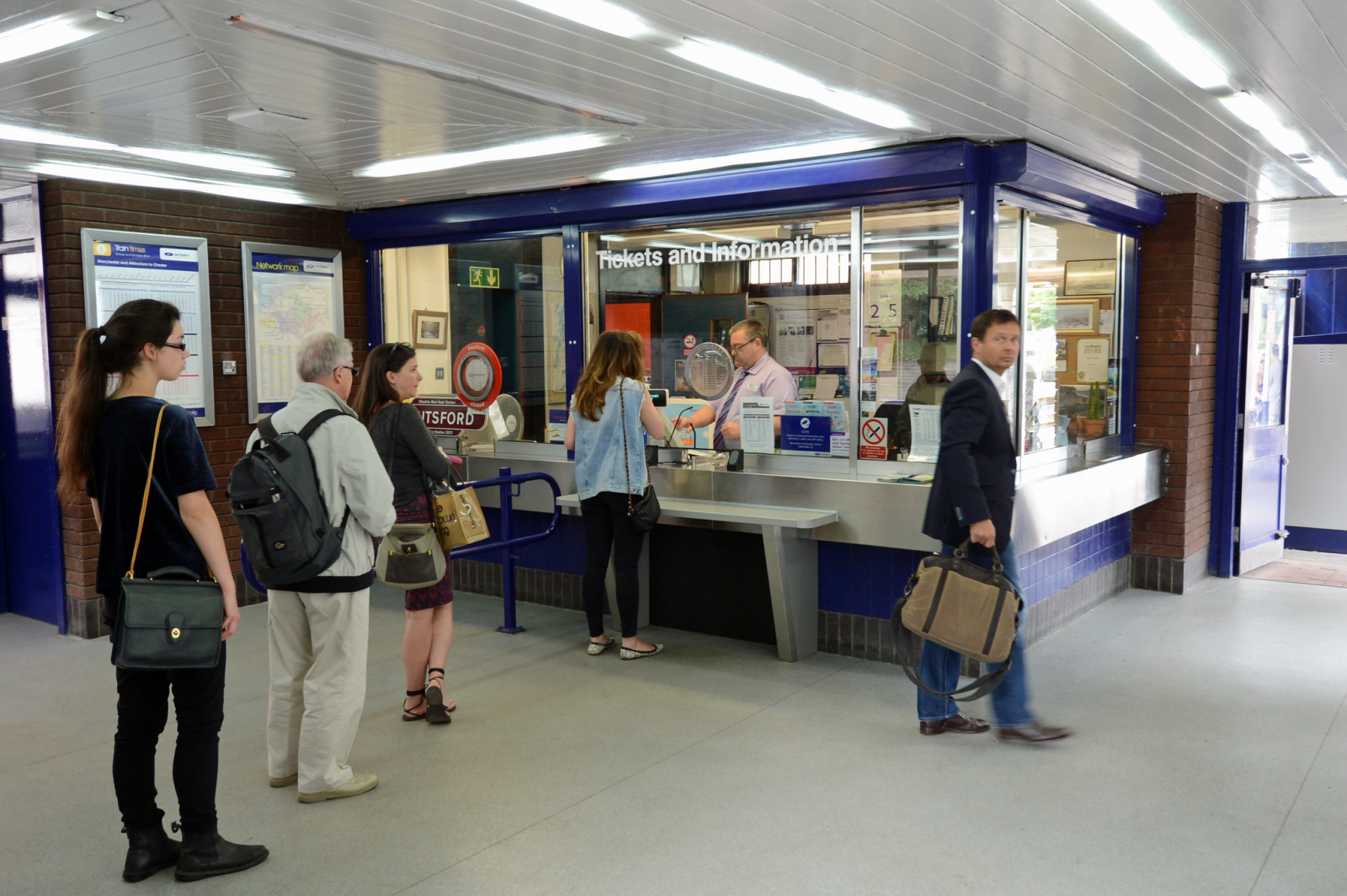 Customers queuing at a local train station ticket office. 
