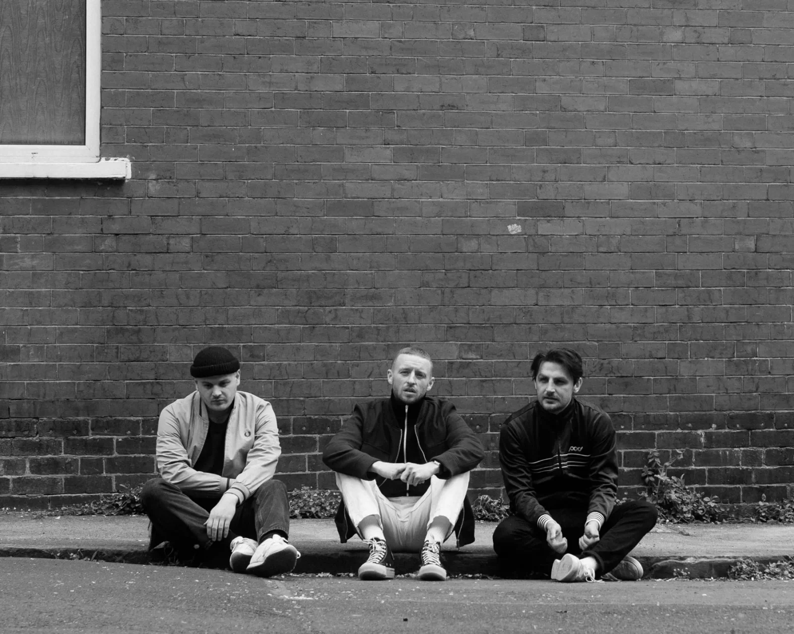 Skinny living band - The three band mates sat on a curb black and whitee picture
