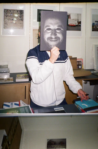 person holding up a piece of paper over their face.