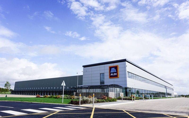 outside of Aldi supermarket building with while walls and a zebra crossing.