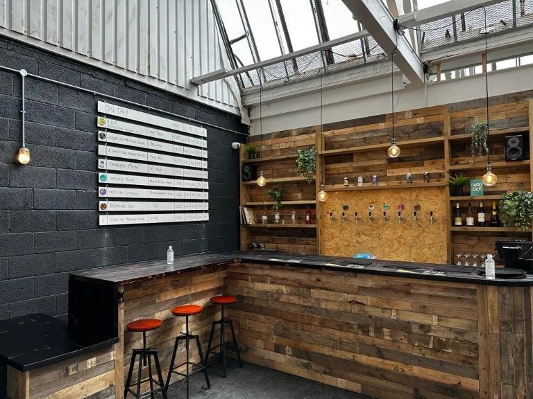 taproom with wooden palettes and red stools.