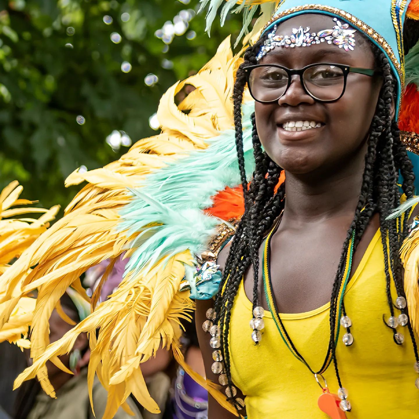 A woman dressed in colourful carnival clothing smiling at the camera.