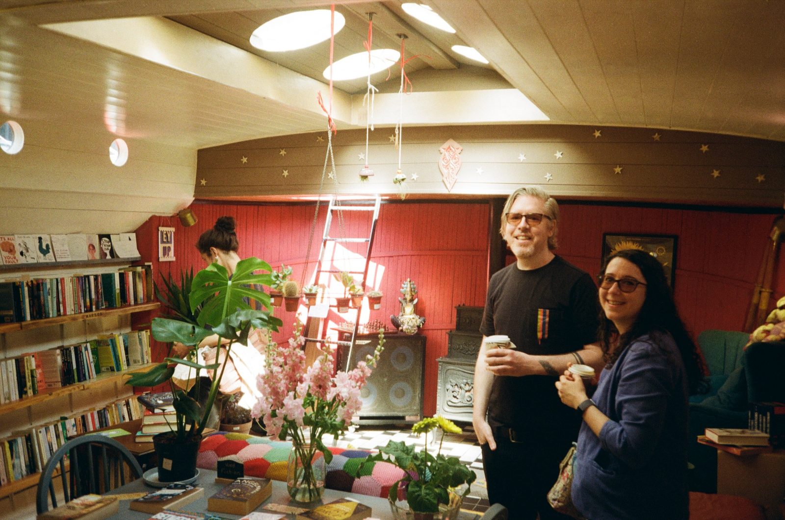 two people smiling at a camera next to books.