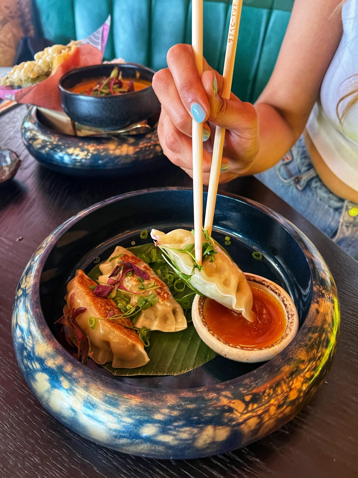 gyozas being picked up with chopsticks.