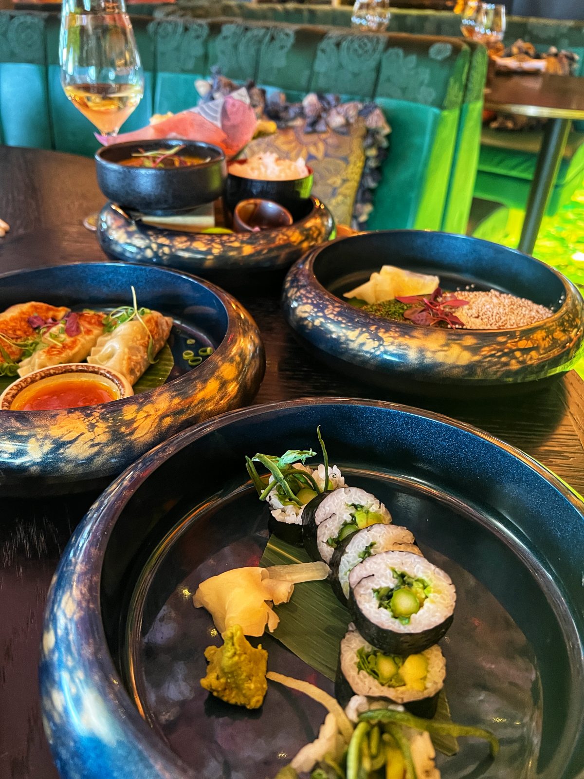 sushi on a plate with a glass of wine in the backgrounds.