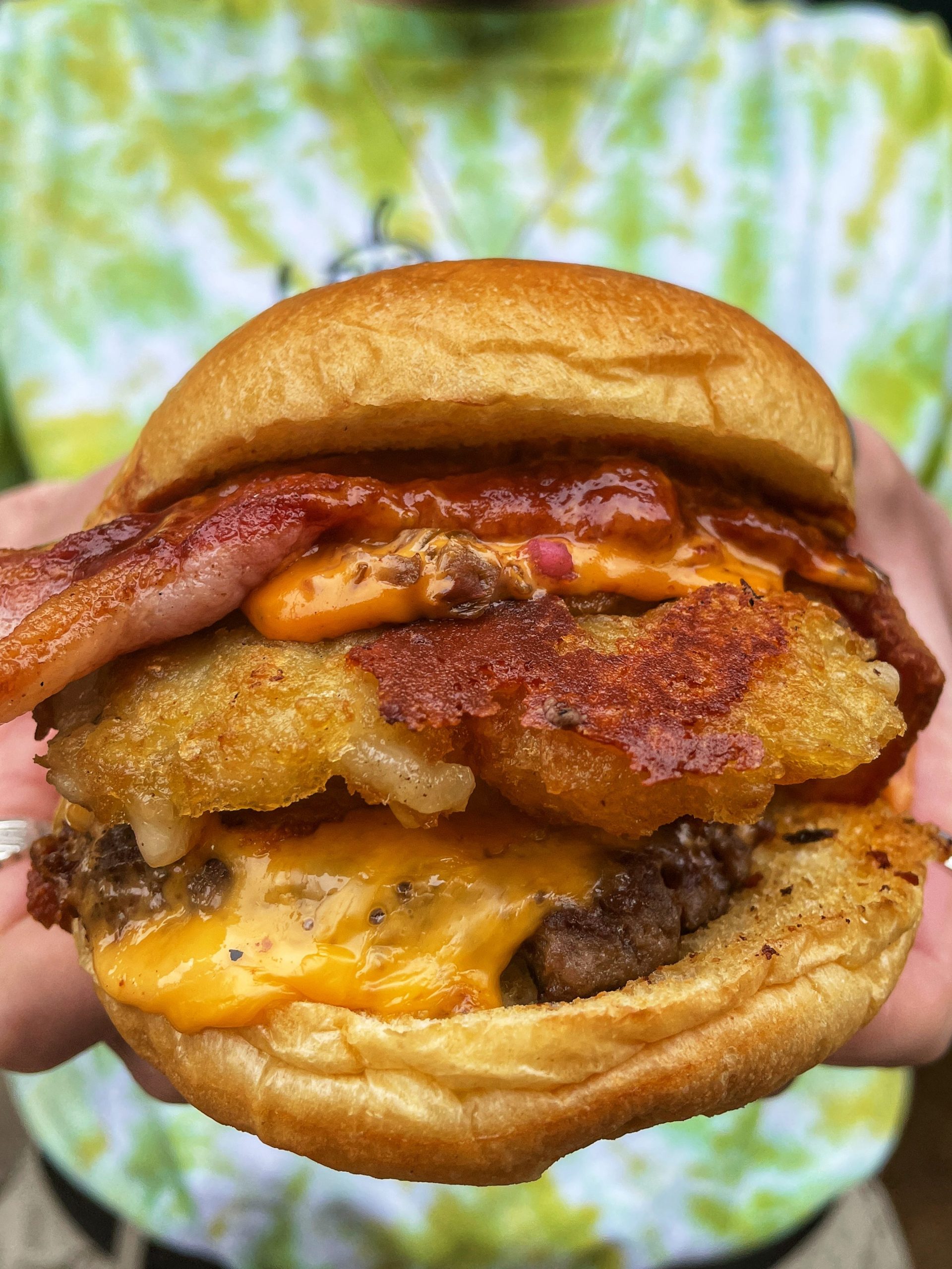 burger with hash brown, bacon, sauce and cheese.
