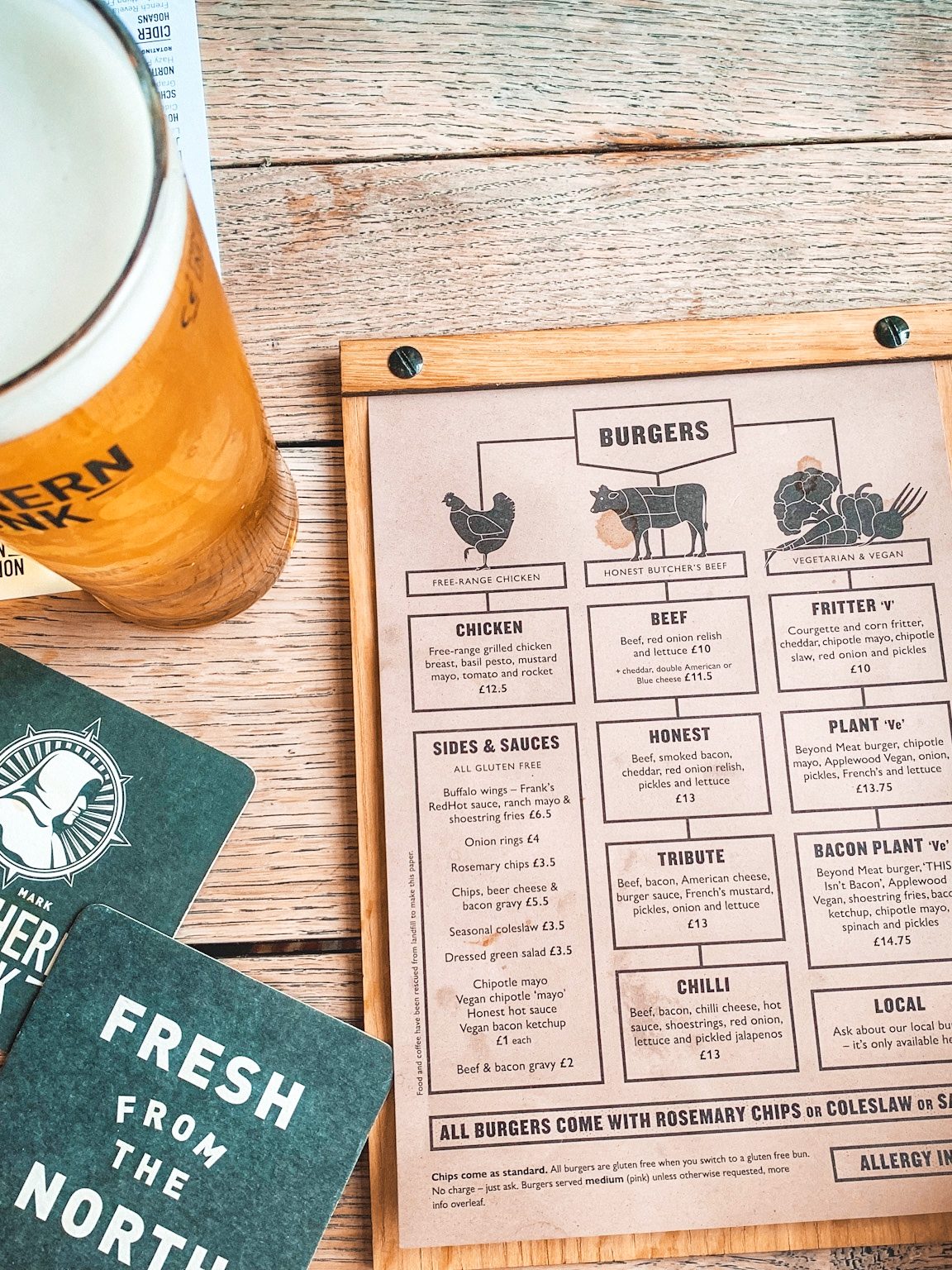menu with chicken, beef and fritter burger options next to two Northern Monk coasters and a pint of beer.