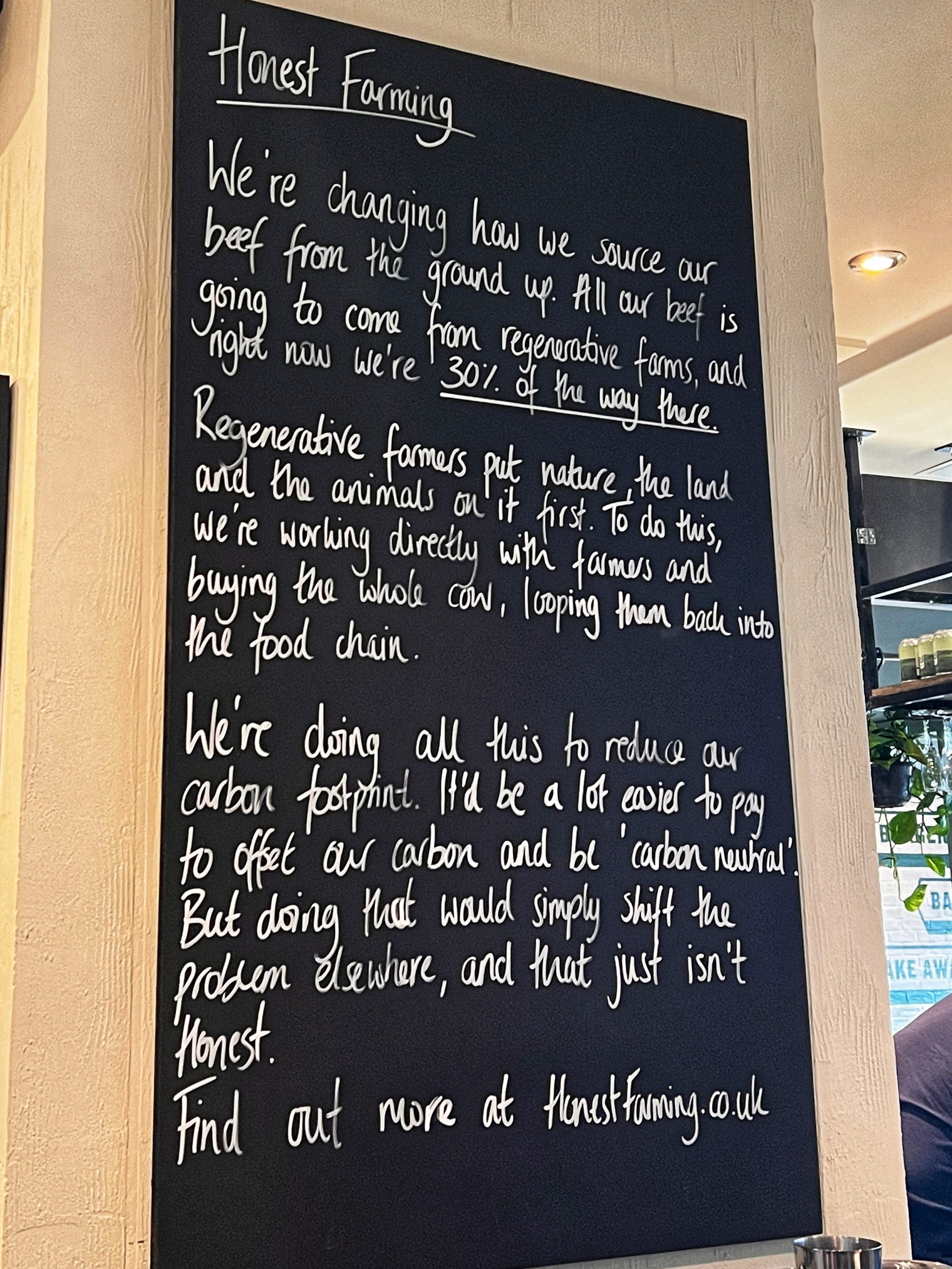 a chalkboard with a handwritten. notice about where Honest Burgers meat comes from.