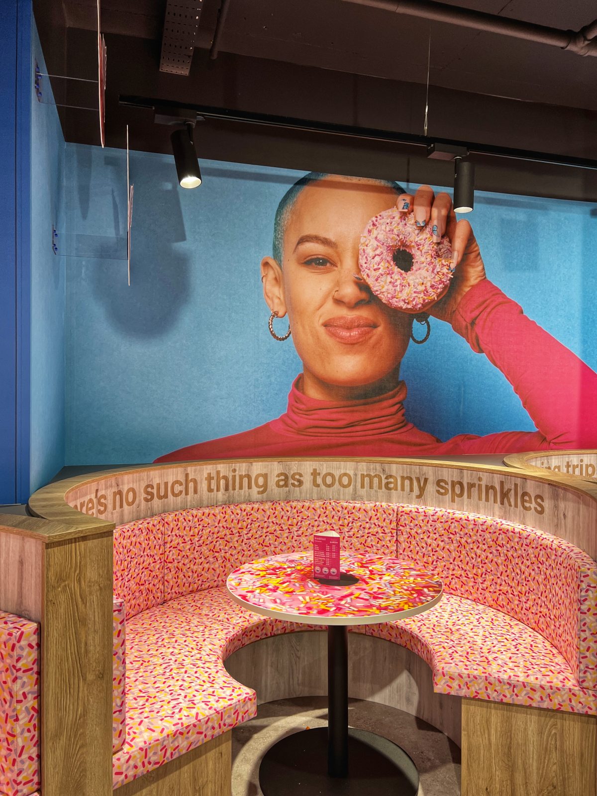 A booth with pink coloured seating in a cafe. 