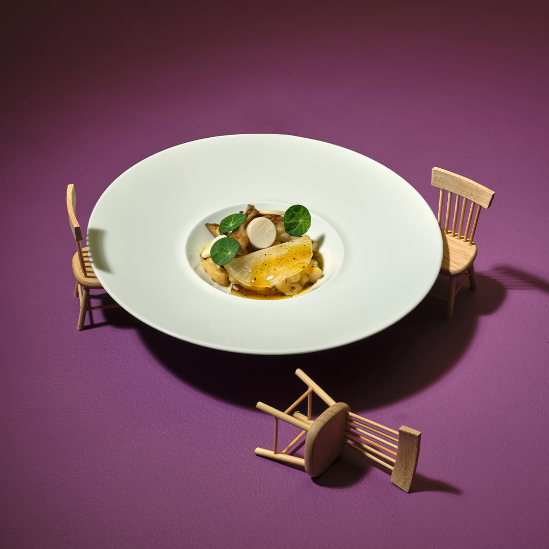 Spaetzle, Barbecue Maitake, White Turnip, Black Garlic Dressing in a bowl with three small chairs on the outside.