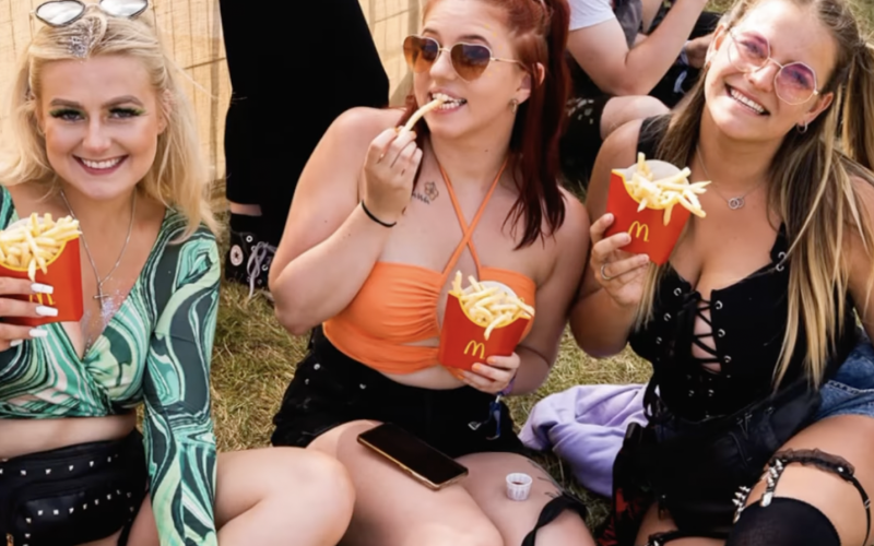 group of people eating McDonalds fries sat on grass.