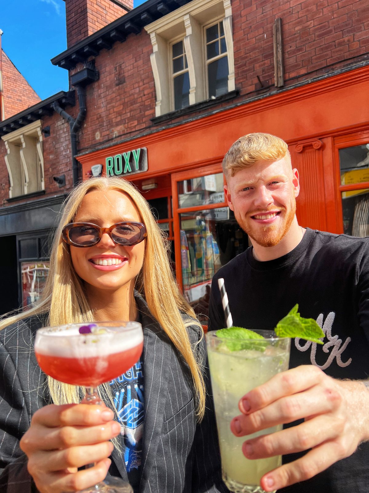 Man and woman cheersing cocktails to the camera. 