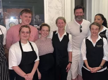 Hugh Jackman smiling for a photo with hotel staff.