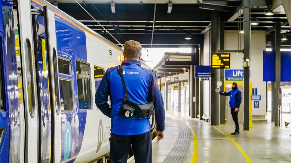 A man stood outside a Northern rail train. 