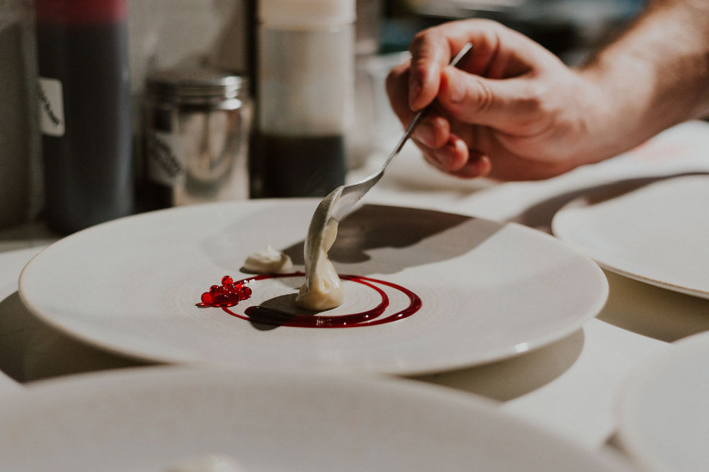 Plating up a raspberry dish with cream on top.