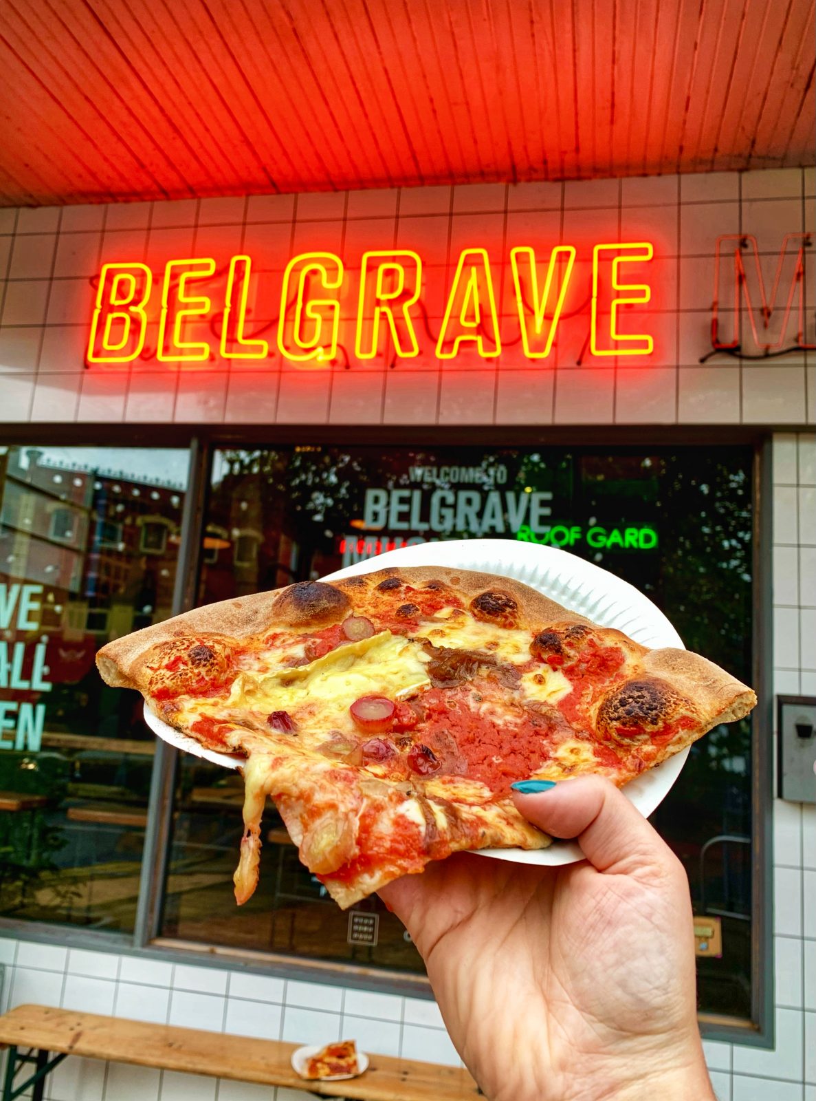 A pizza slice being held up outside Belgrave Music Hall in Leeds. 